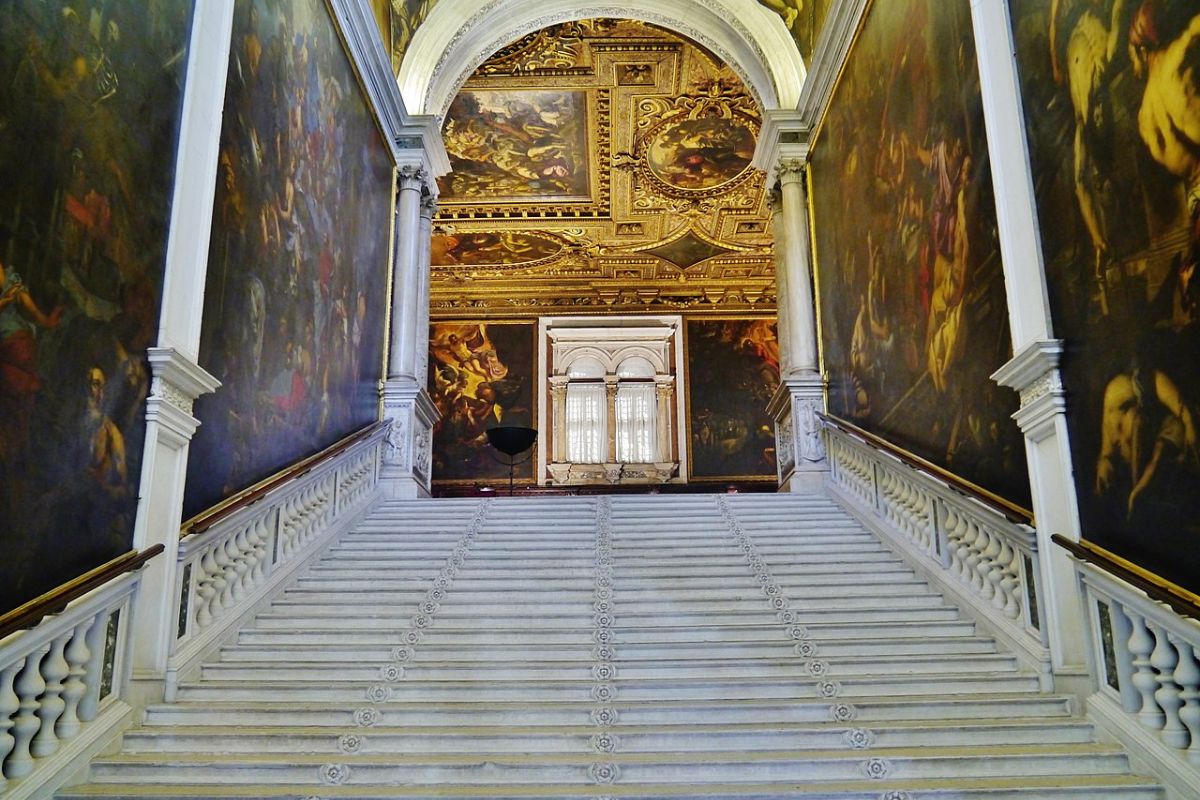 Den monumentale trappen i Scuola Grande di San Rocco i Venezia, dekorert med fargerik marmor og historiske inskripsjoner.