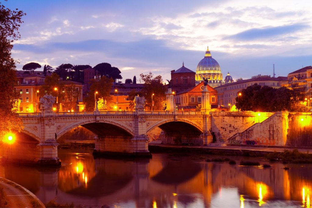 Peterskirken i Roma sett om kvelden bak en bro over Tiber-elven – ikonisk utsikt over Italias hovedstad