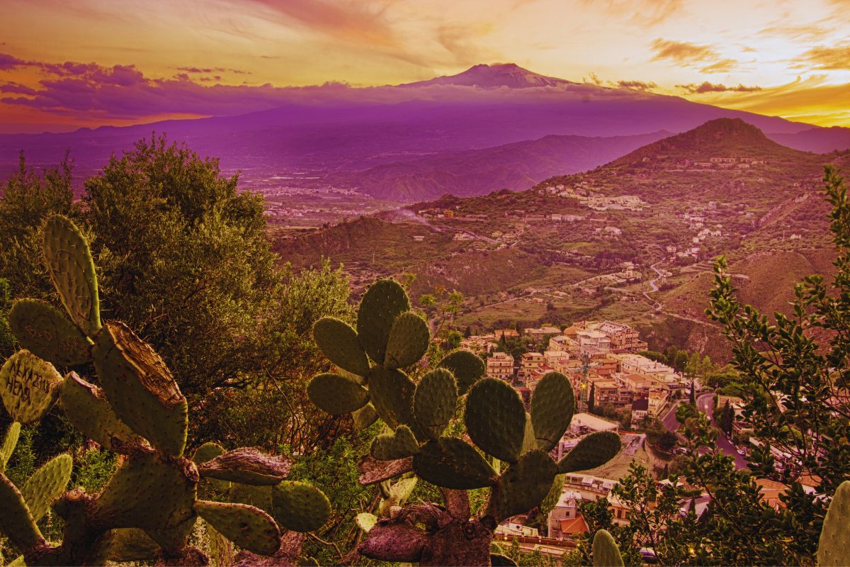 Solnedgang over Sicilia med utsikt mot Etna, landsbyer og fikenkaktus