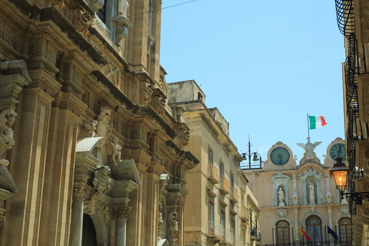 Utsikt over en gate i gamlebyen i Trapani, Sicilia, med barokke bygninger og middelhavsstemning.
