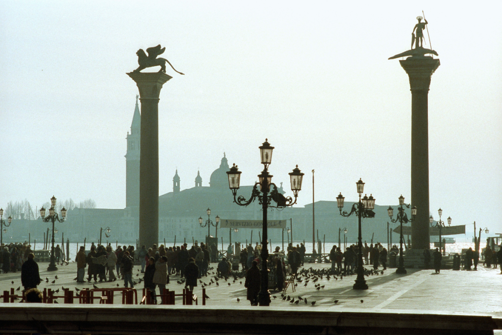 Søylen med løven av San Marco på Markusplassen i Venezia, med utsikt mot havet og gyllent morgenlys