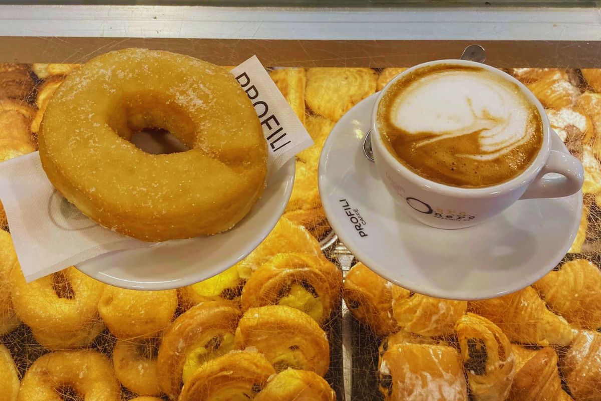 Ciambella og cappuccino Cappuccino og ciambella på italiensk bar – klassisk frokost i Italia med bakverk i bakgrunnen.
