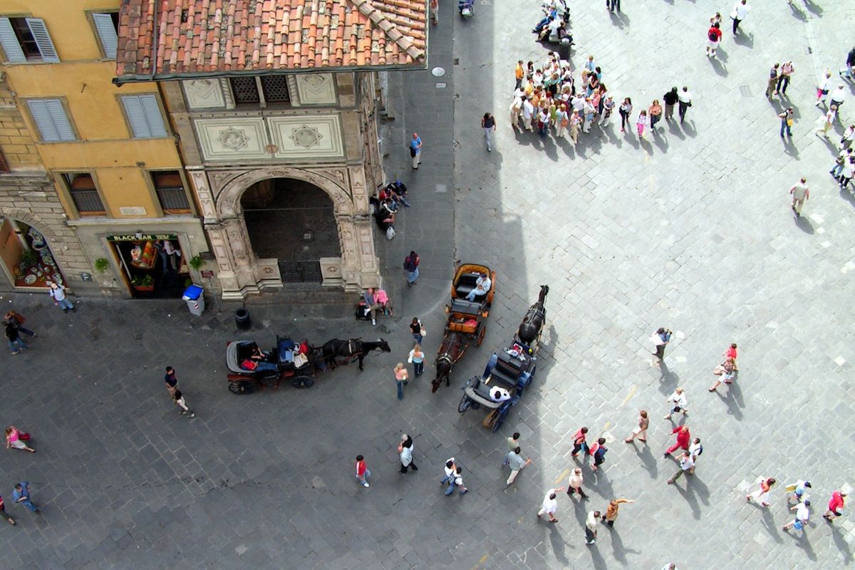 Folkeliv i gamlebyen i Firenze sett ovenfra – med turister, hestekjerrer og historiske bygninger i sentrum av byen.