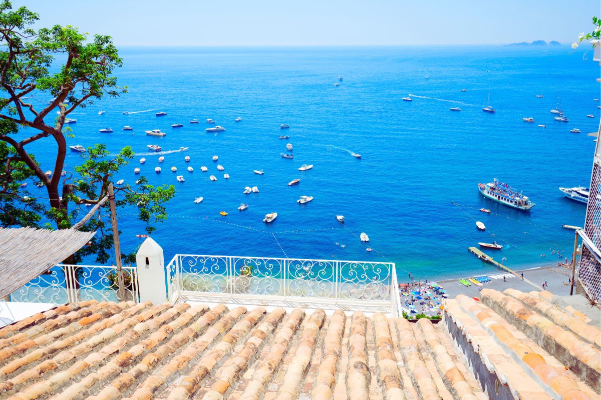 Utsikt mot stranden og båtene i Positano sett fra en terrasse med tegltak