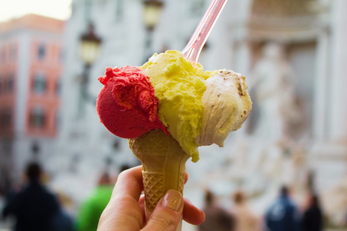 Tre kuler med italiensk iskrem i kjeks – bringebær, sitron og hasselnøtt – foran Trevifontenen i Roma.