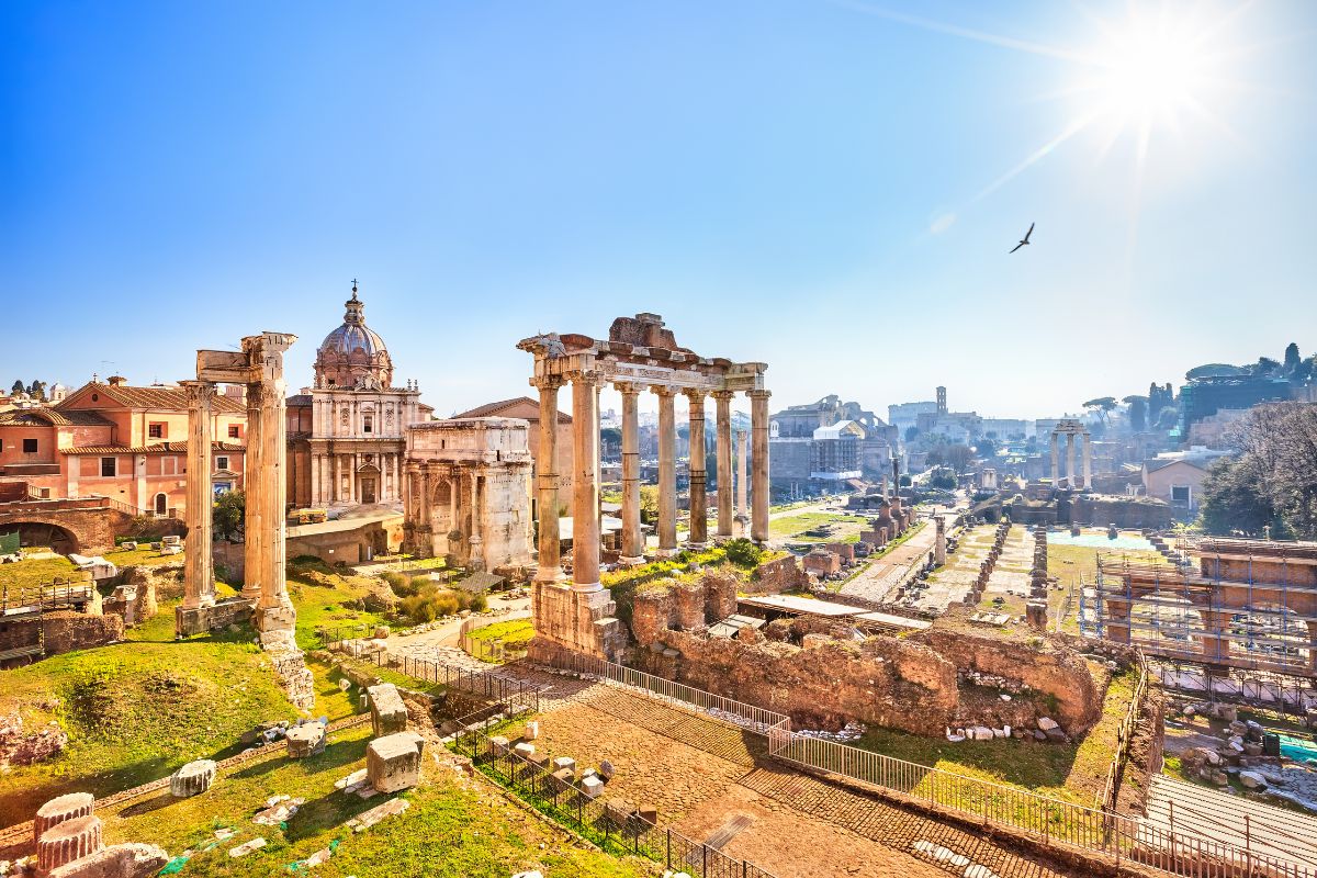Forum Romanum i Roma, med antikke søyler, ruiner og kirker under en klar, solrik himmel.