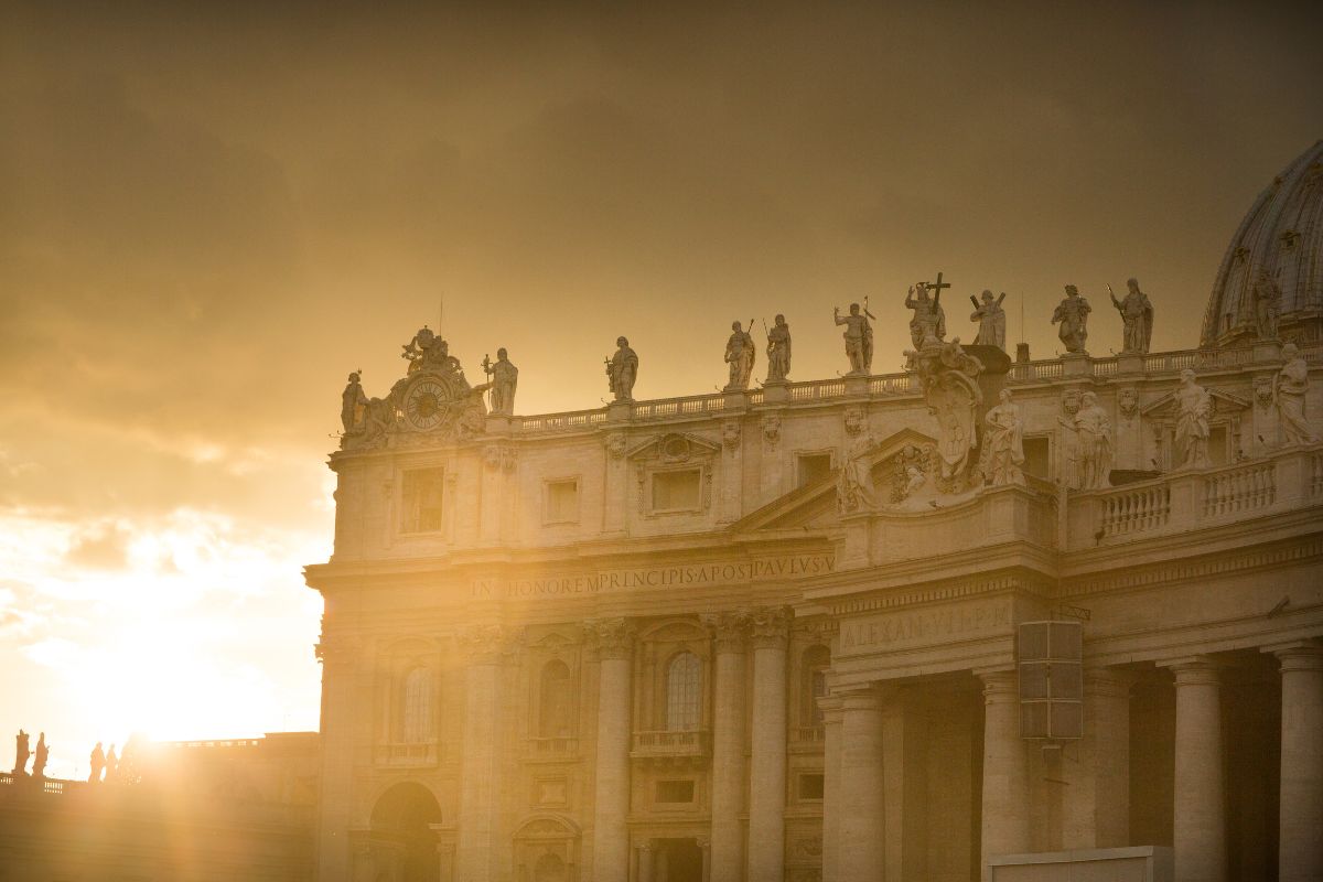 Fasaden til San Giovanni in Laterano i Roma, opplyst av gyllent kveldslys, med statuer som troner på toppen.