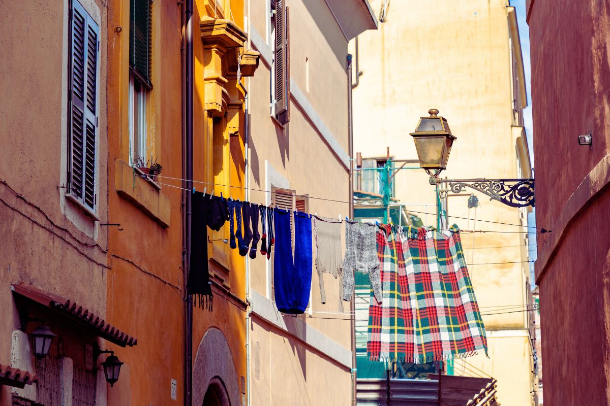 Fargerike bygårder i en smal gate i Trastevere, Roma, med klesvask som henger til tørk mellom husene.