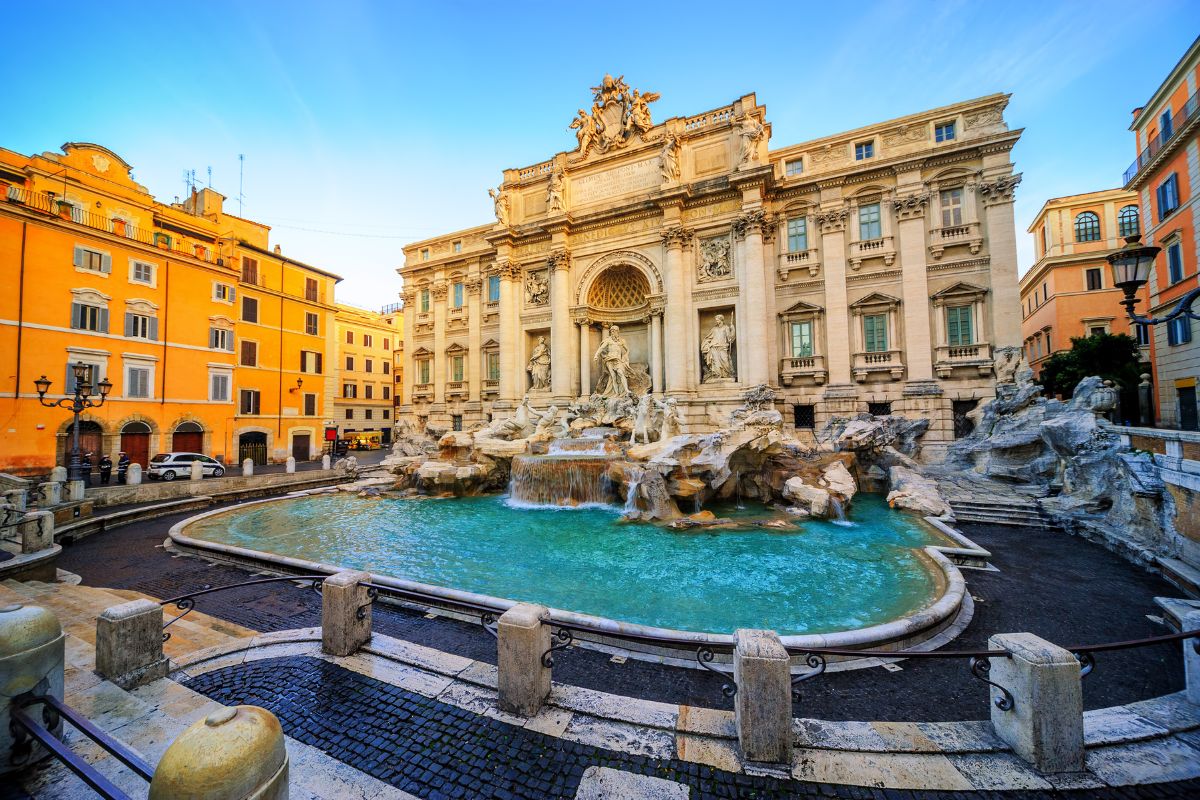 Trevifontenen i Roma, med barokkarkitektur, skulpturer og turkisblått vann omgitt av historiske bygninger.