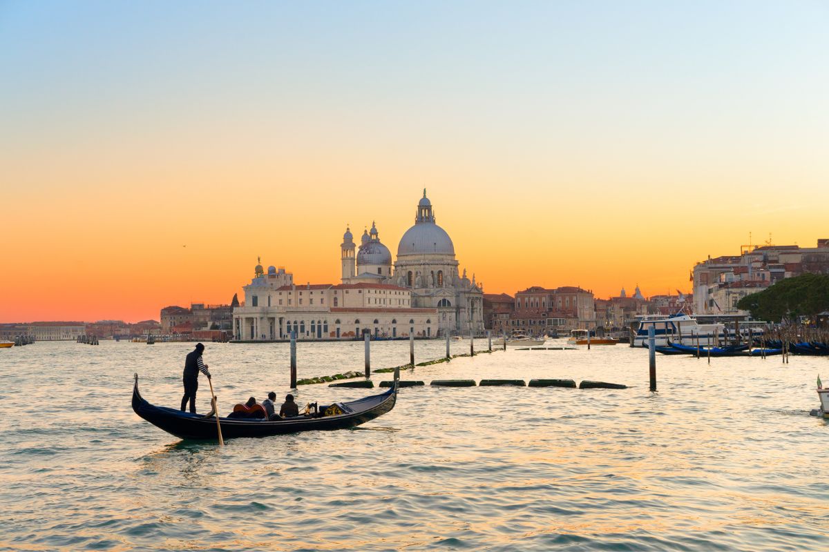 Venezia Utsikt over Venezia ved solnedgang med en gondol på Canal Grande og Santa Maria della Salute i bakgrunnen.