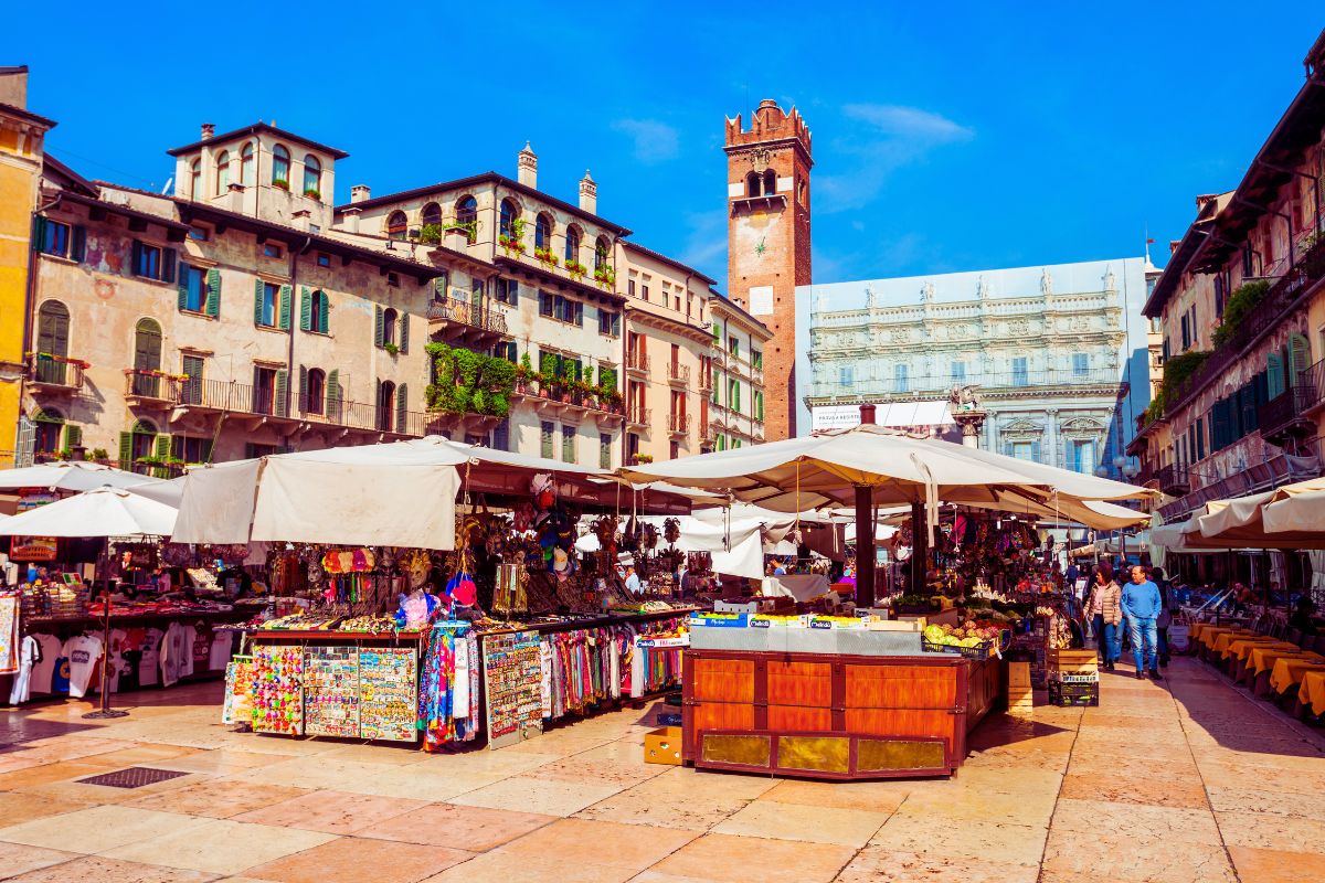Piazza delle Erbe i Verona med markedsboder, historiske bygninger og tårn – byens mest livlige torg og et av høydepunktene i gamlebyen.