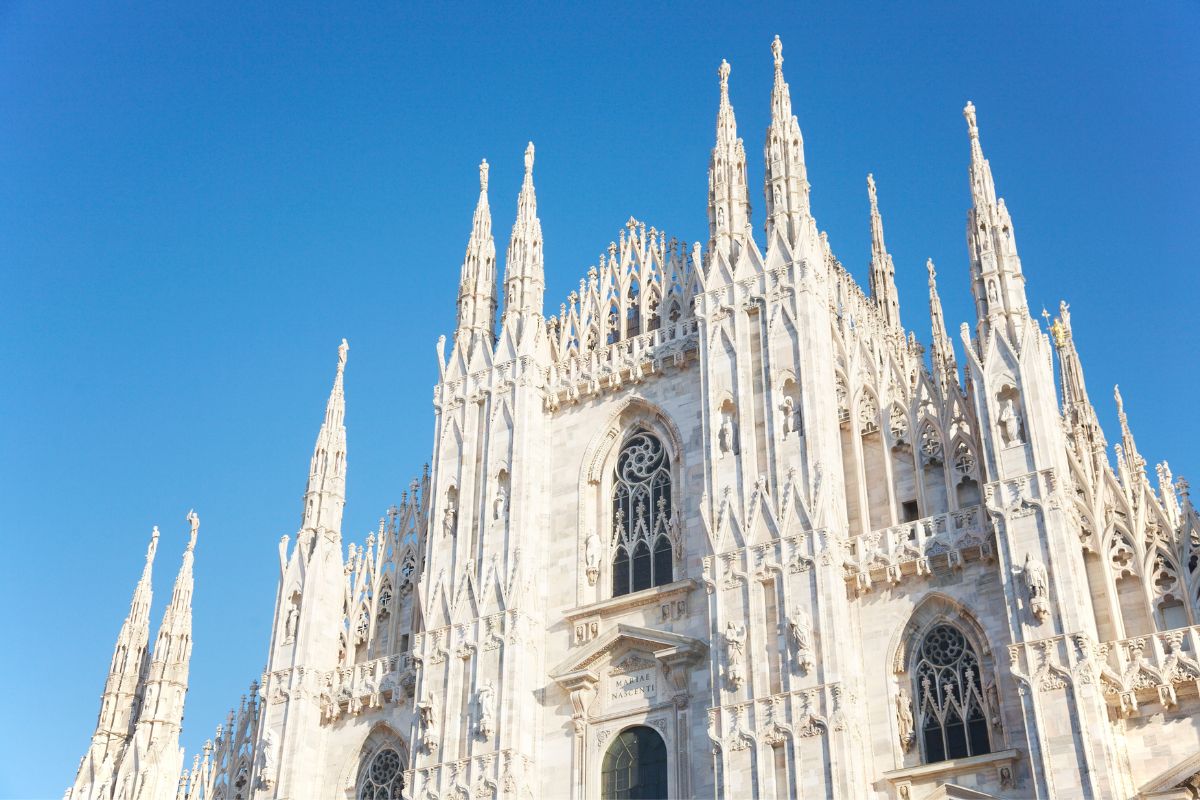 Den praktfulle fasaden til Milanos katedral (Duomo di Milano) under en klar blå himmel.
