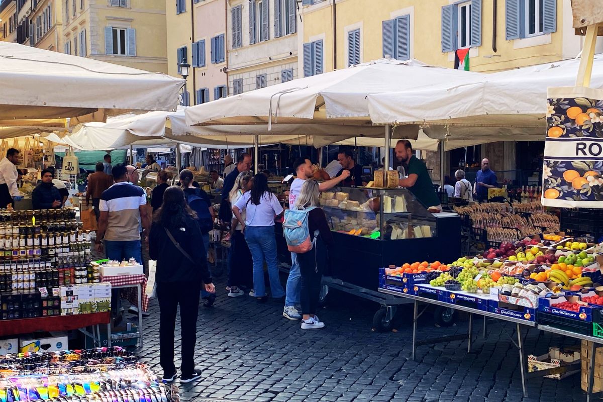 Markedet på Campo de’ Fiori i Roma, fullt av boder med ost, frukt, grønnsaker og lokale produkter – et klassisk sted å handle ingredienser til italienske retter som pasta all’amatriciana.