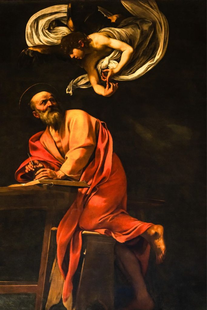 Evangelisten Matteus sitter og skriver mens en engel viser ham veien ovenfra. Maleri av Caravaggio med dramatisk lys og sterk kontrast.