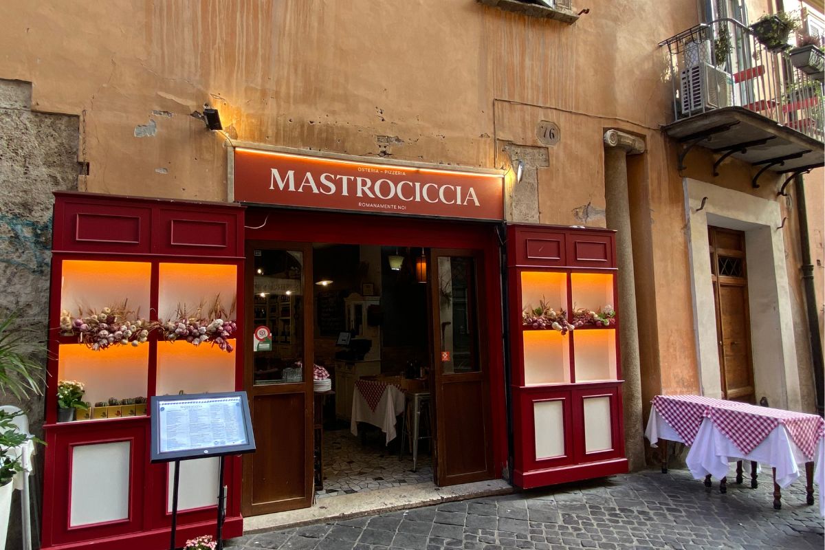 En typisk romersk osteria i sentrum av Roma, med rutete duker og varm atmosfære – det perfekte stedet å spise en ekte pasta all’amatriciana.