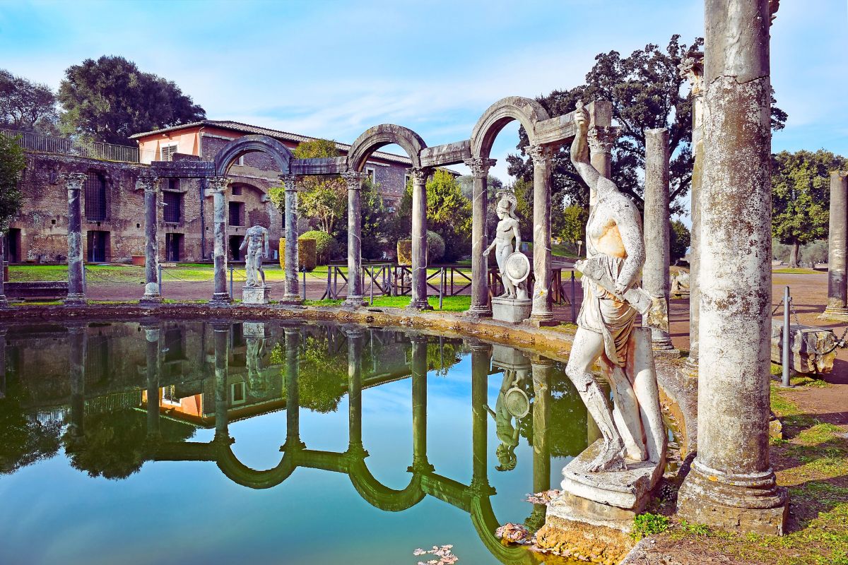 Antikke romerske ruiner i Villa Adriana (Tivoli) med søyler, statuer og en refleksjonsdam – historisk spa- og badeanlegg.