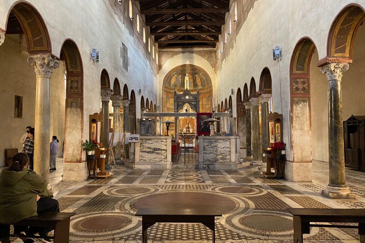Interiør av Santa Maria in Cosmedin i Roma med marmorsøyler, cosmatesk gulv og middelalderske fresker i apsiden