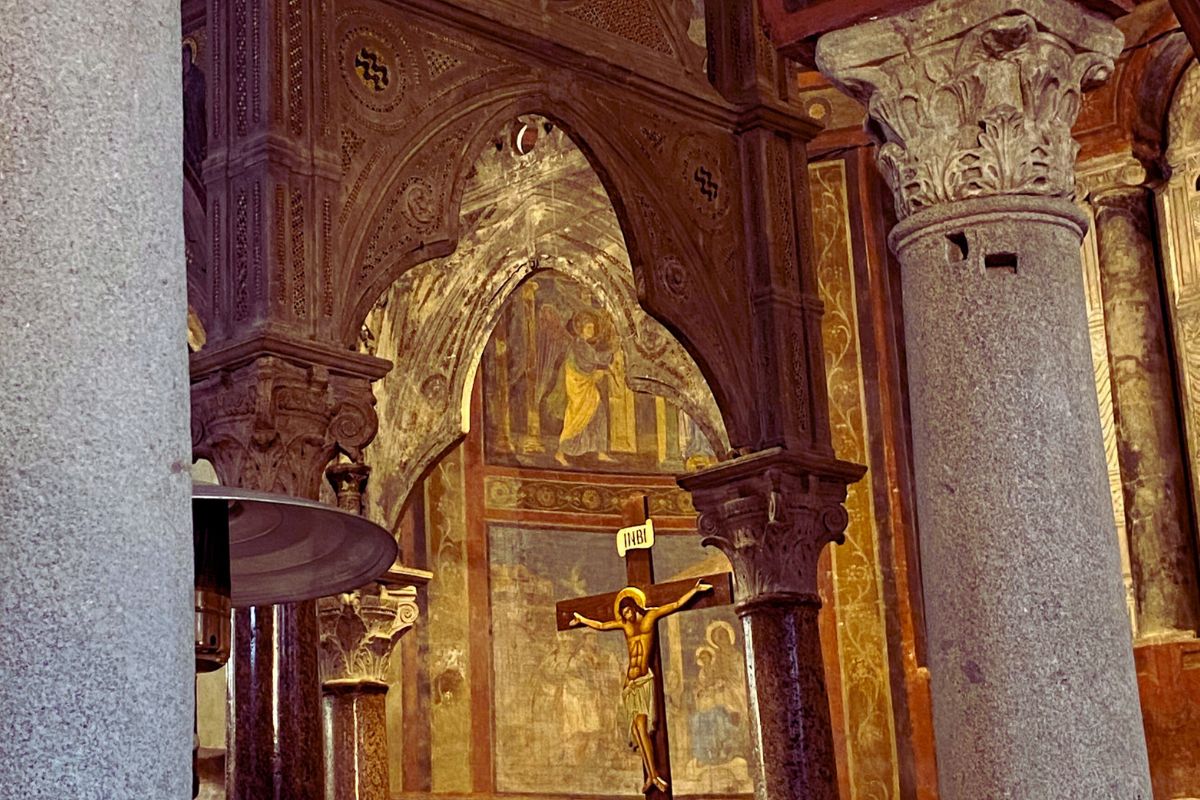 Detaljer fra interiøret i Santa Maria in Cosmedin i Roma, med middelalderske fresker, marmorsøyler og et krusifiks.