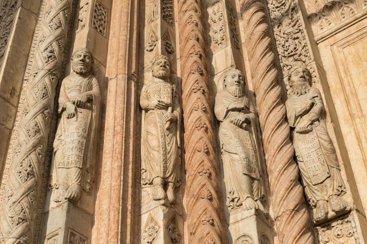 Skulpturer av profeter på fasaden til Duomo di Verona, med romanske søyler og rikt utskårne steindetaljer.