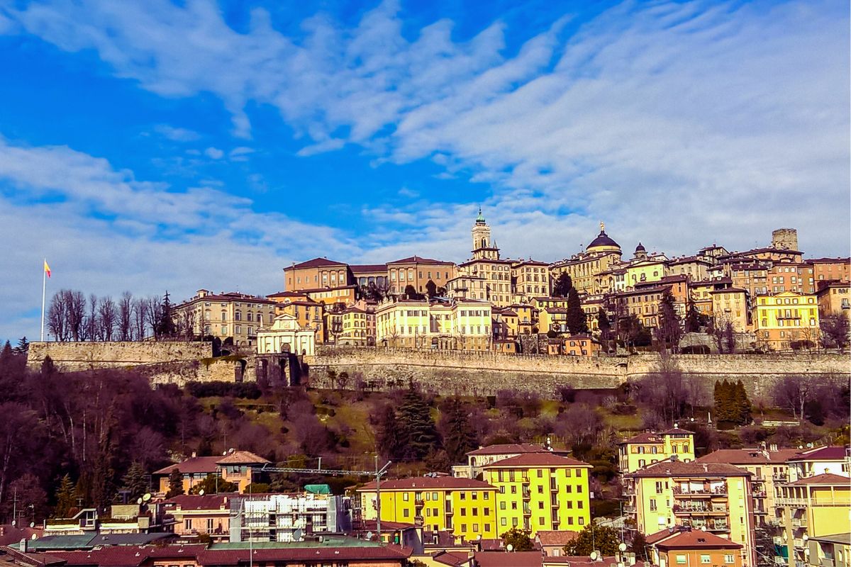 Bergamo Città Alta sett fra byen nedenfor, med de historiske bymurene og gamle bygninger på høyden.