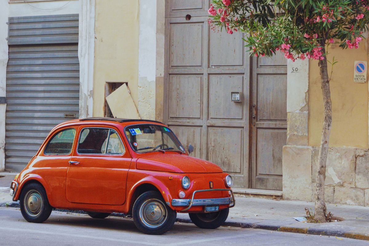 Rød vintage Fiat 500 parkert i en gammel italiensk gate.