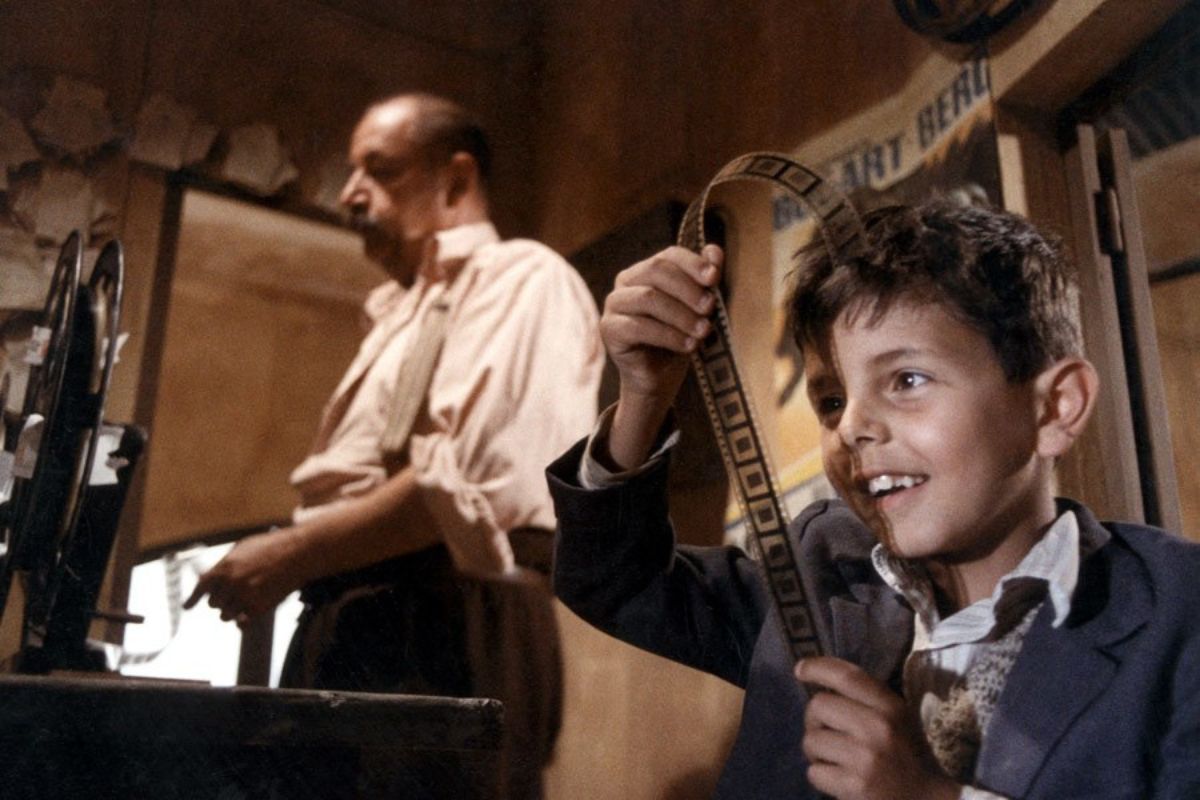 Totò som barn holder en filmrull inne i kinoen sammen med kinomaskinisten Alfredo i filmen Nuovo Cinema Paradiso