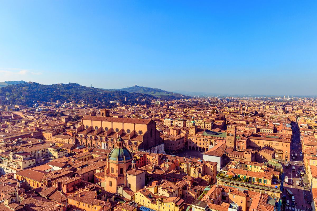 Utsikt over Bologna sett ovenfra, med historiske bygninger, kirketak og de karakteristiske røde hustakene i bykjernen.