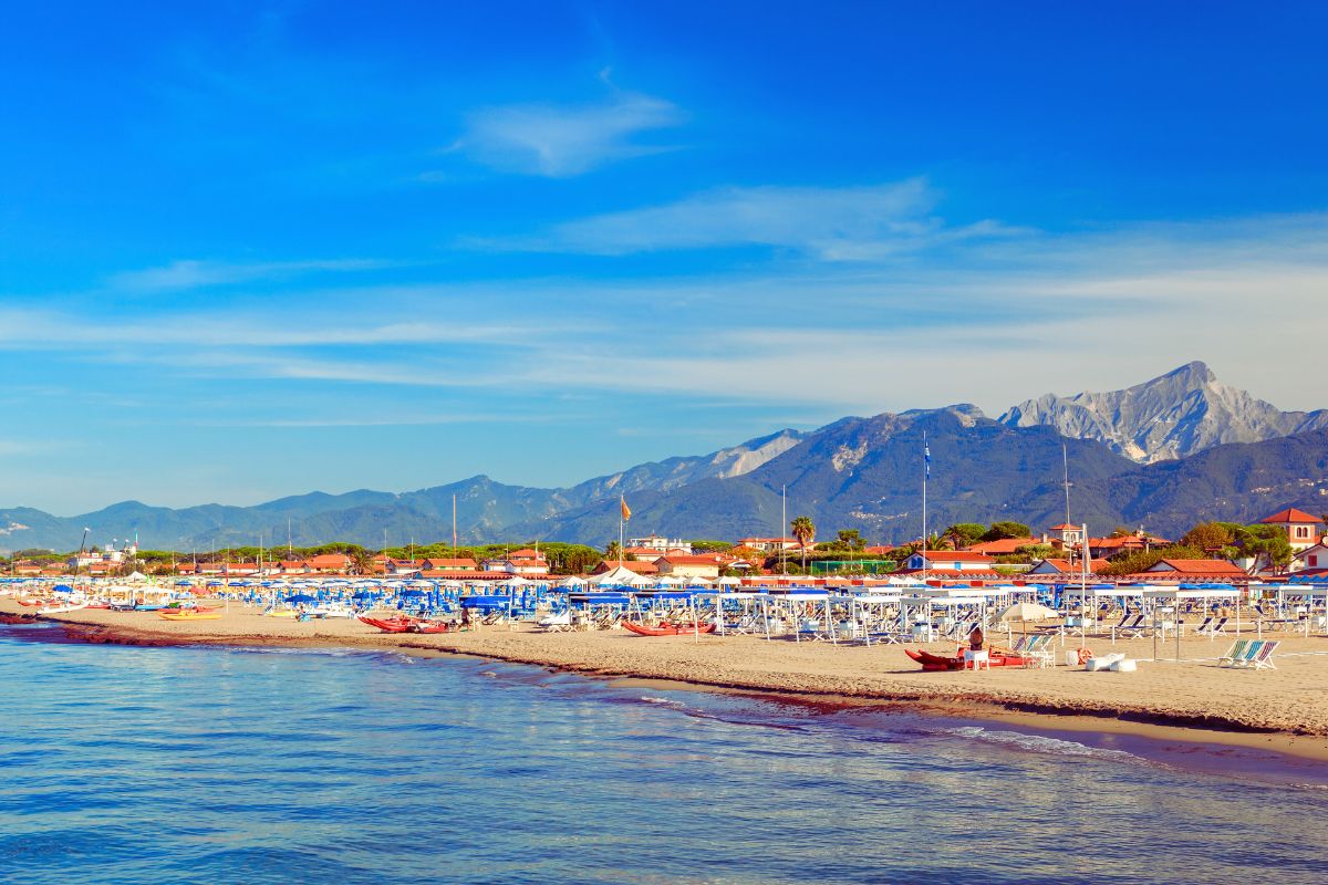 Forte dei Marmi i Toscana med strand, badehytter og fjellene i bakgrunnen.