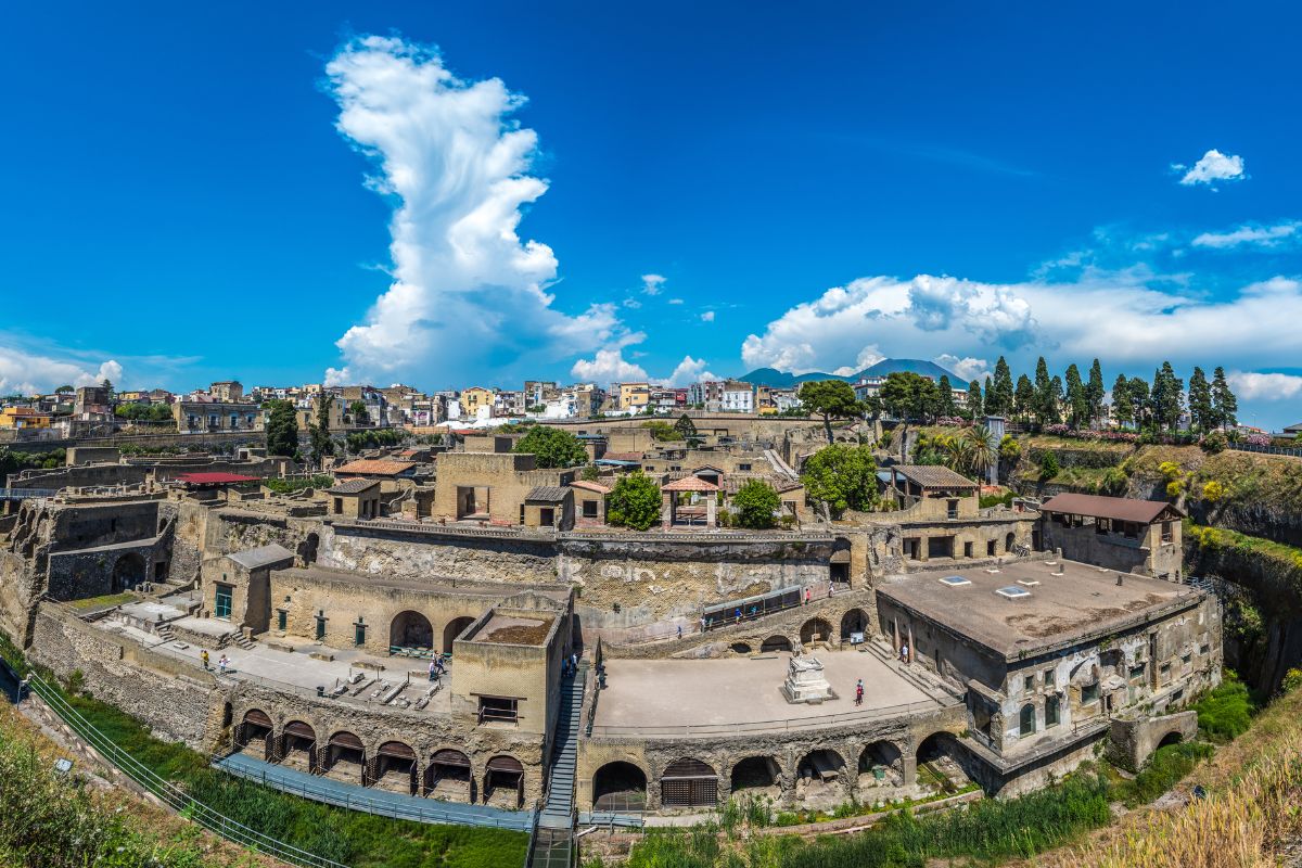 Oversiktsbilde av Herculaneum med godt bevarte romerske bygninger og den moderne byen i bakgrunnen.