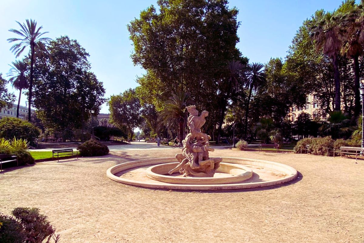 Fontene i Piazza Vittorio Roma med skulptur omgitt av trær og park.
