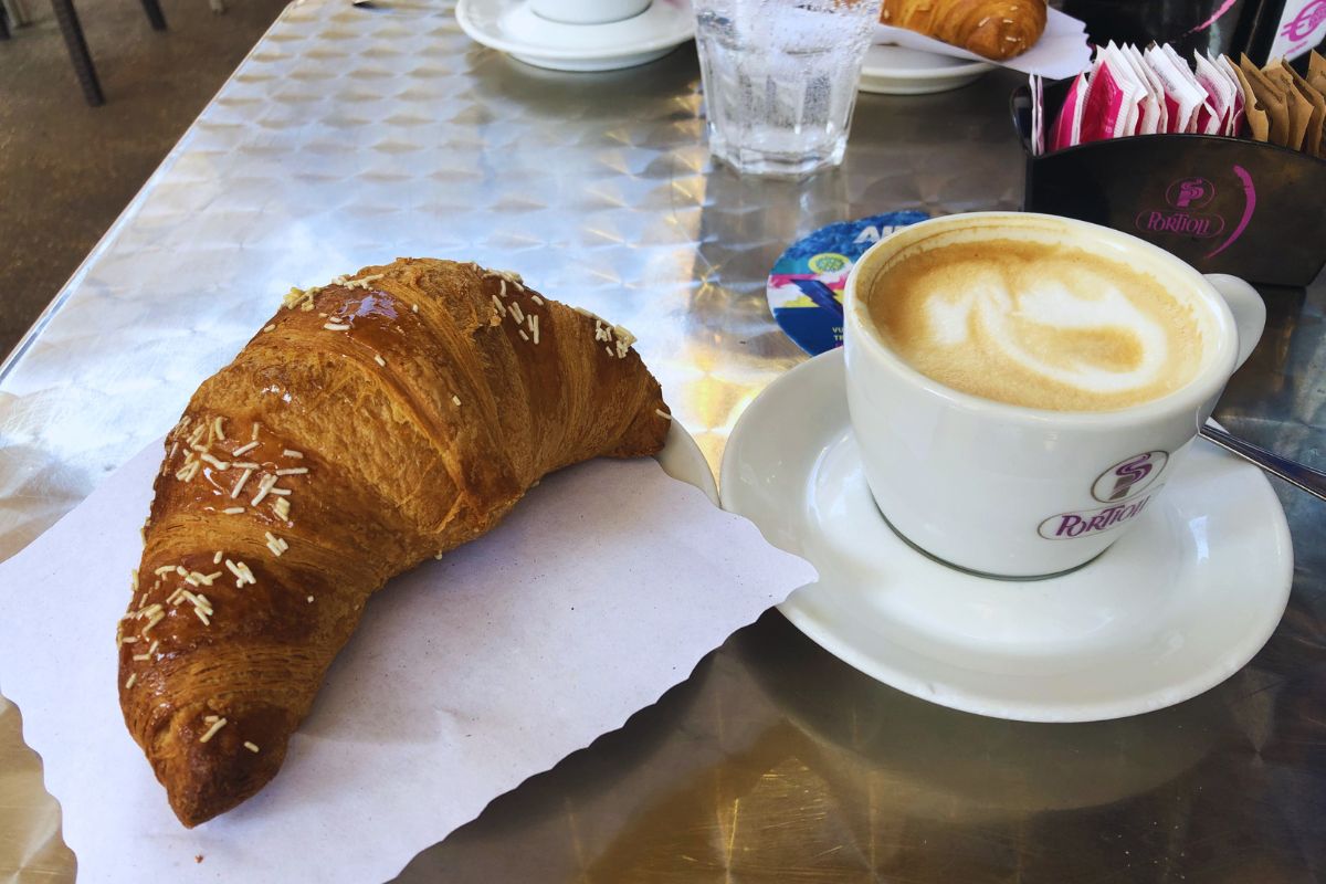 Tradisjonell italiensk frokost med cappuccino og cornetto på en kafé i Italia. Italienske mattradisjoner, morgenkaffe og typisk italiensk livsstil.