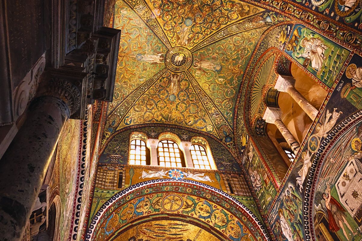 Interiøret i San Vitale-basilikaen i Ravenna med rikt dekorerte bysantinske mosaikker, gyldne detaljer og kuppelen sett nedenfra.