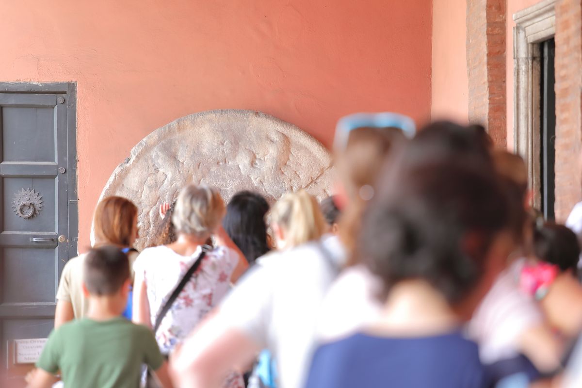Turister i kø foran Bocca della Verità i Roma, et av de mest besøkte og fotograferte stedene i byen.