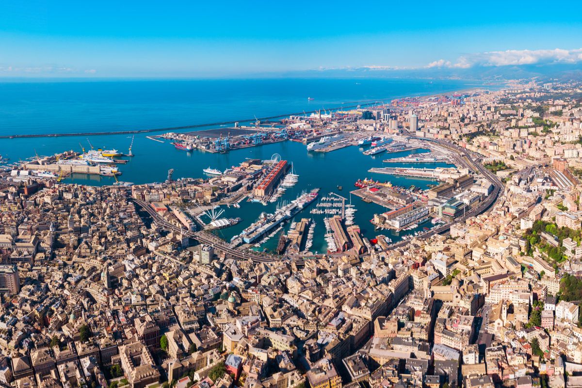 Luftfoto av Genova med den historiske gamlebyen, den store havnen og Middelhavet som strekker seg ut mot horisonten. Byen er Ligurias hovedstad og en av de viktigste havnebyene i Italia.