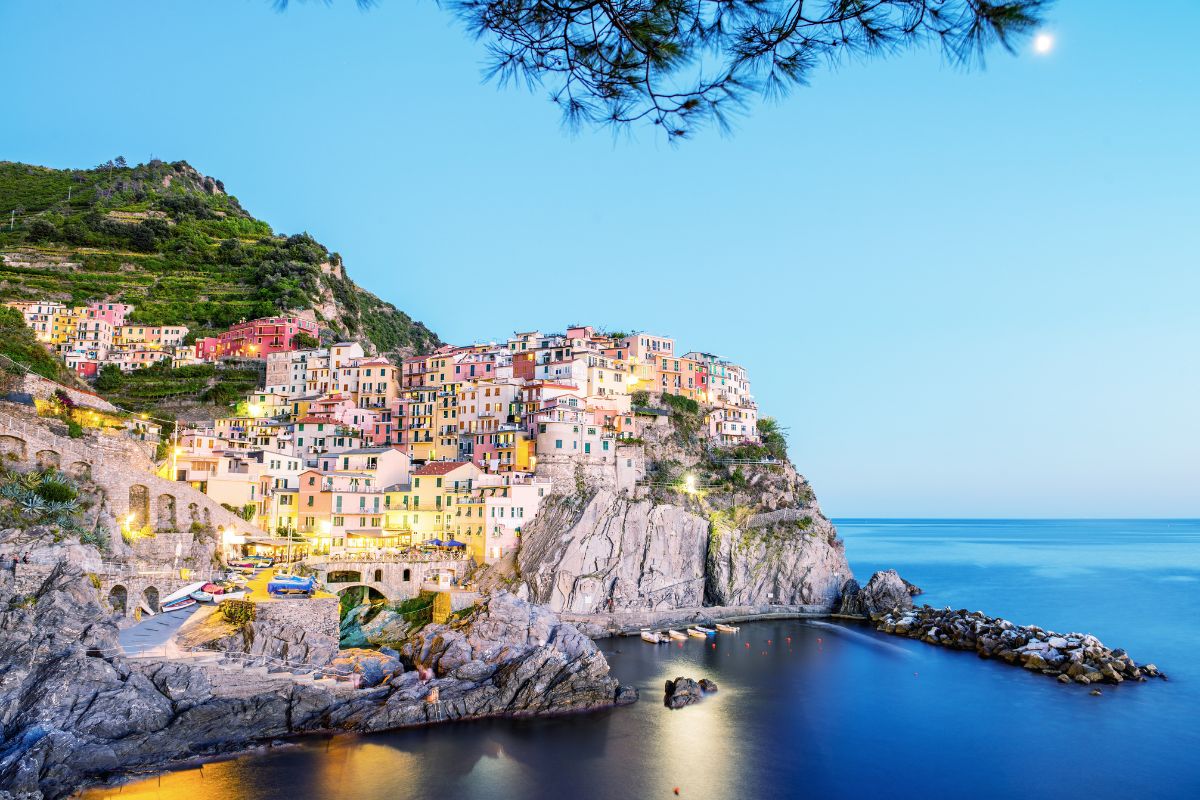 Manarola i Cinque Terre ved solnedgang, med fargerike hus bygget direkte på klippene over Middelhavet. Landsbyen er kjent for sin spektakulære beliggenhet, sine smale gater og de vakre utsiktene som har gjort Cinque Terre berømt over hele verden.
