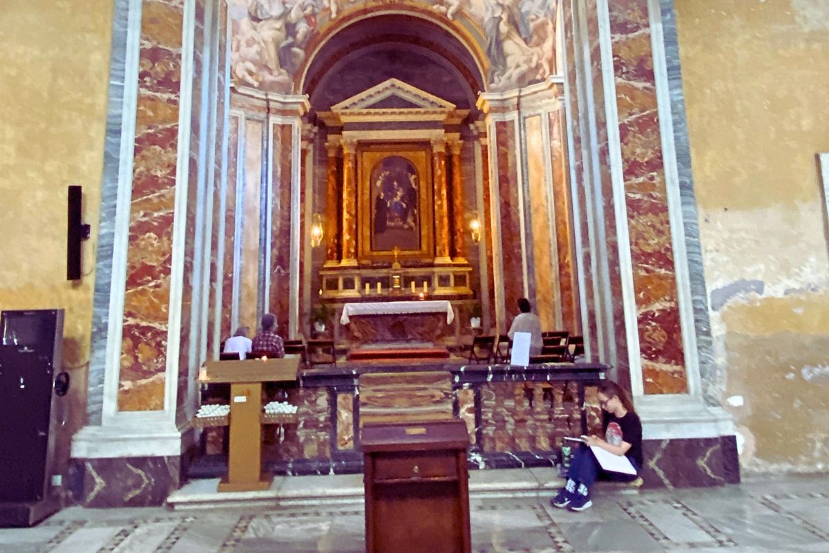 Sidekapell i basilikaen Santa Sabina i Roma med marmoralter, barokkutsmykning og besøkende som studerer og ber.
